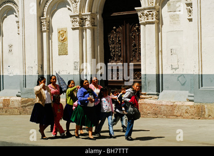 Ecuador, Cuenca, view of a family walking on sidewalk against arched entrance Stock Photo