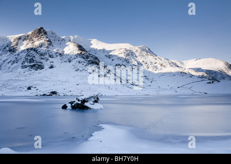 View across frozen Llyn Idwal lake to Y Garn in mountains of Snowdonia National Park (Eryri) in winter 2010. Cwm Idwal Ogwen Gwynedd North Wales UK Stock Photo