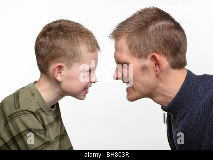 closeup of father and preteen son with angry faces close together Stock Photo