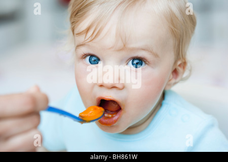 baby being fed looking at viewer Stock Photo