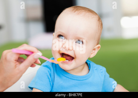 baby sitting in chair being fed Stock Photo