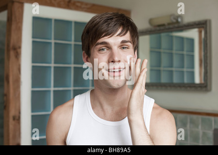 A man applying face cream in the bathroom Stock Photo