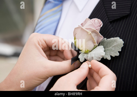 Detail of a woman pinning a corsage to a jacket lapel Stock Photo