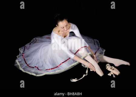 A ballet dancer putting on her pointe shoe Stock Photo