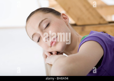 A ballet dancer resting her head on her arms at the barre in a ballet studio Stock Photo