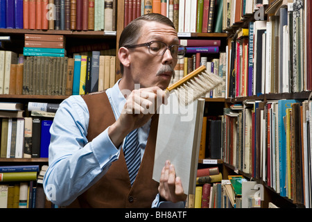 A man using a dust brush on a book Stock Photo