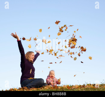 mother and baby throwing autumn leaves