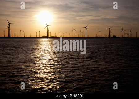 View of wind turbines over water at sunset Stock Photo