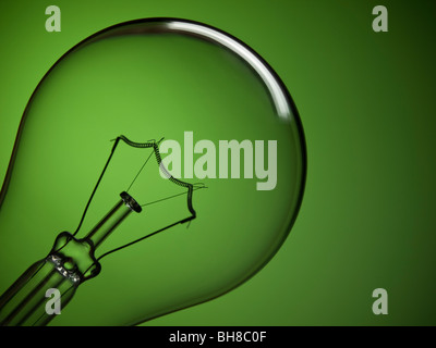 Close up on a transparent light bulb over a green background. Stock Photo