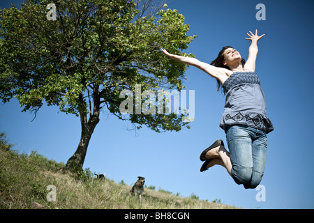 Woman leaping by tree Stock Photo