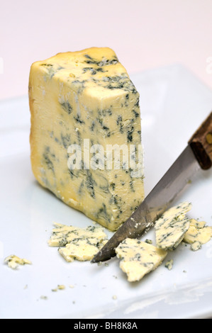 Cutting Danish Blue Cheese with knife on plate Stock Photo