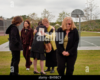 The mother of a young adult suicide is hugged by well-wishers at an outdoor memorial service in Laguna Beach, CA. Stock Photo