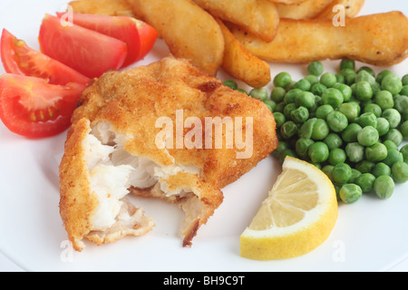 A meal of a breaded white fish fillet with chunky fried potato wedges, peas, tomato and lemon Stock Photo