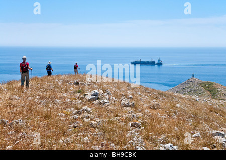 Walkers on a ridge descending to the Lighthouse at the tip of Cape Tenaro in the deep Mani, Peloponnese, Greece Stock Photo