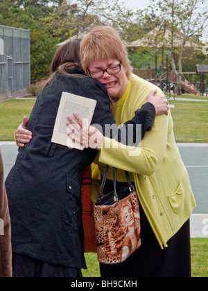 The mother of a young adult suicide is hugged by well-wishers at an outdoor memorial service in Laguna Beach, CA. Stock Photo