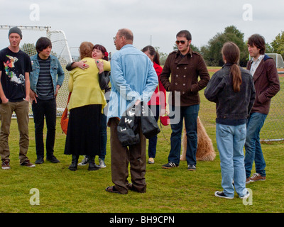 Surrounded by friends of her late daughter, the mother of a young adult suicide is hugged by well-wishers at an outdoor memorial Stock Photo