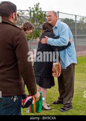 The father of a young adult suicide is hugged by well-wishers at an outdoor memorial service in Laguna Beach, California. Stock Photo