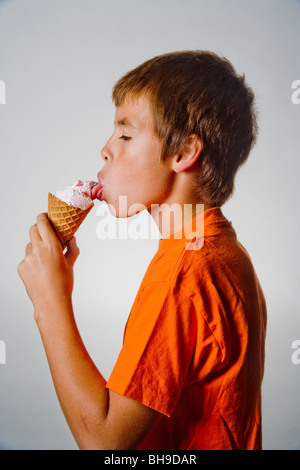 A happy ten year old boy licks a scoop of ice cream in a waffle cone. Stock Photo