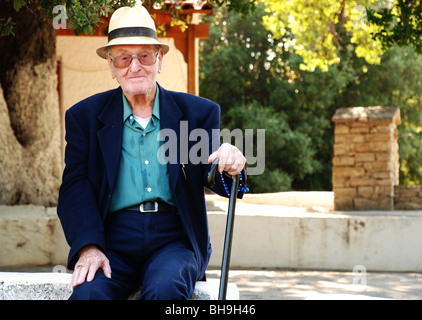old man in a suit sitting on a wall outside Stock Photo