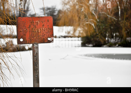 no Swimming sign next to iced lake Stock Photo