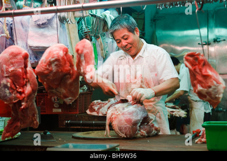 A butcher on Causeway Bay's Bowrington Road's street market prepares cuts of meat in the early morning in Hong Kong. Stock Photo