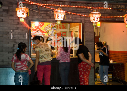 Beijing, CHINA- Hutong Neighborhood, Lit up at Night, 'Chinese Restaurant' Women Ordering at Window of Take out Shop, Small Shop Night, women friends china city Stock Photo