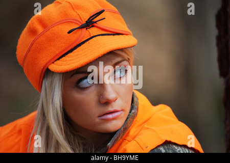 PORTRAIT YOUNG WOMAN 21 Y.O. FEMALE HUNTER IN FOREST WEARING ORANGE BLAZE STORMY KROMER HAT Stock Photo