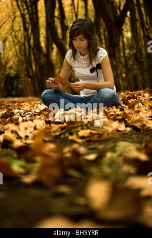 Beautiful woman seated on the ground in a beautiful Autumn Park