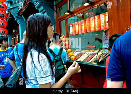 Beijing, China - Young Chinese, profile view, Woman Eating Local Specialty on Stick in Public Market  Street Stock Photo