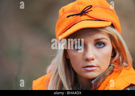 PORTRAIT YOUNG WOMAN 21 Y.O. FEMALE HUNTER IN FOREST WEARING ORANGE BLAZE STORMY KROMER HAT Stock Photo