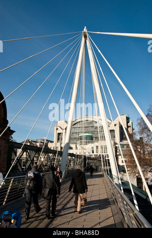 Walking across Hungerford Bridge across the River Thames in London looking to Charing Cross Railway Station Stock Photo