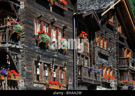 Traditional wooden houses / chalets with geraniums in summer in the Swiss Alpine village Grimentz, Valais / Wallis, Switzerland Stock Photo