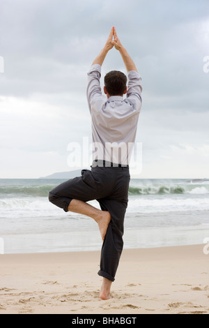 Businessman doing relaxation exercises on a beach Stock Photo