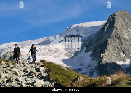 Two female hikers walking along mountain path in the Pennine Alps / Walliser Alpen, Valais / Wallis, Switzerland Stock Photo