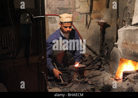 Sanaa, Yemen. A young man forges metal in the furnace, the traditional way. Chewing qat and at night. Stock Photo