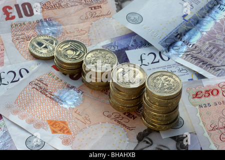 Five piles of one pound coins in increasing height on a background of fifty, twenty and ten pound notes. Stock Photo