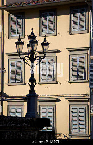 Shuttered windows on a typical Italian building, with the silhouette of an ornate lamppost in the foreground, Florence, Italy Stock Photo