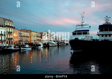 In Sète. France's largest Mediterranean fishing port, buildings glow at sunset beside trawlers moored in the Royal Canal