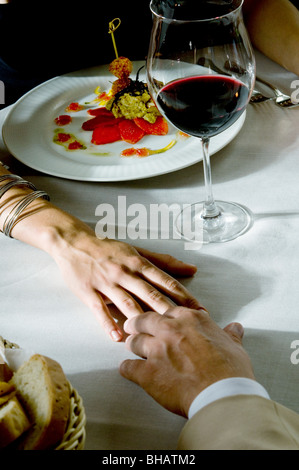 Closeup of couple's hands touching at dinner table Stock Photo
