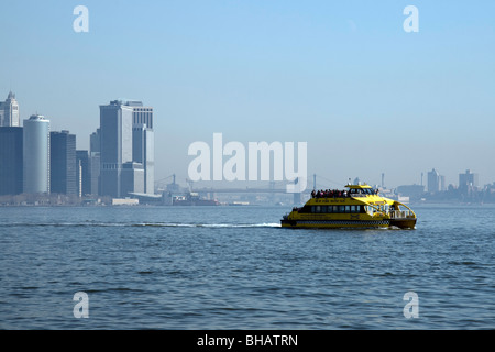 A water taxi speeds across the water with the lower Manhattan skyline and bridges visible in the background Stock Photo