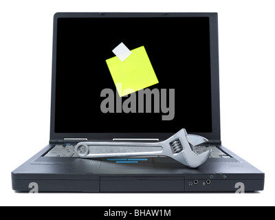 Laptop with a yellow sticky note and a spanner over the keyboard. Isolated on white. Stock Photo