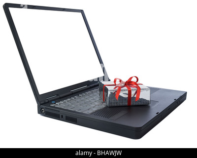 Small gift wrapped with a red ribbon over a black laptop isolated on white. White copy space on screen. Stock Photo