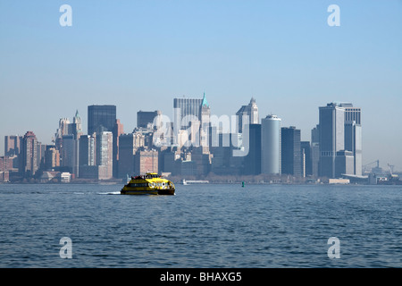 A water taxi speeds across the water on a hazy sunny day with the lower Manhattan skyline in the background Stock Photo