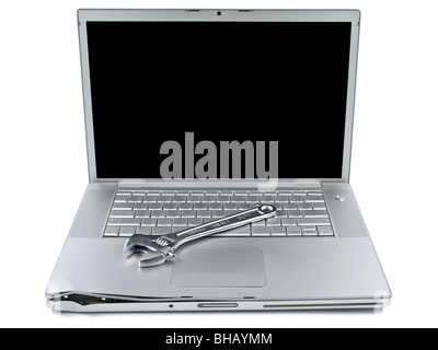 A spanner over a damaged laptop isolated over white background. Stock Photo