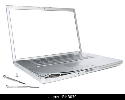 A damaged laptop computer is about to be fixed with a pair of clockwork screwdrivers. Isolated on white. Stock Photo