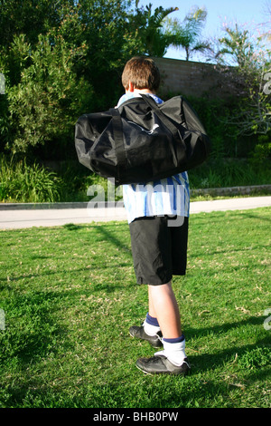 Footballer carrying his kit bag leaves field Stock Photo
