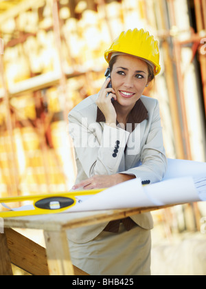 female architect talking on mobile phone in construction site Stock Photo