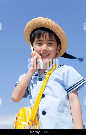 Japan, Tokyo Prefecture, Boy wearing straw hat using mobile phone, portrait Stock Photo