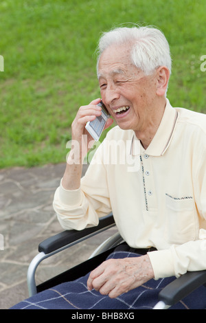Japan, Tokyo Prefecture, Senior man in wheelchair using mobile phone, close-up Stock Photo