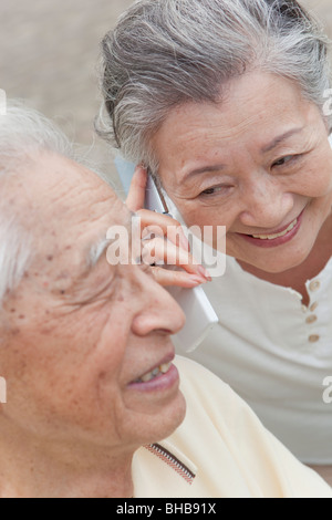 Japan, Tokyo Prefecture, Senior couple using mobile phone, smiling, close-up Stock Photo